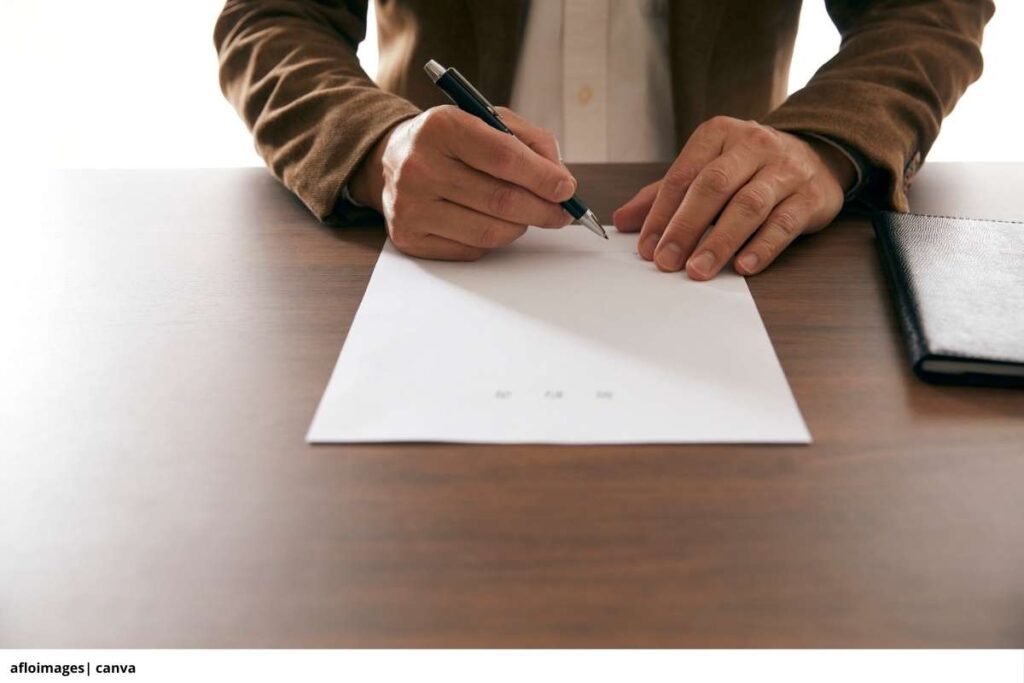 Imagen de una mano firmando un documento de compra de una moto